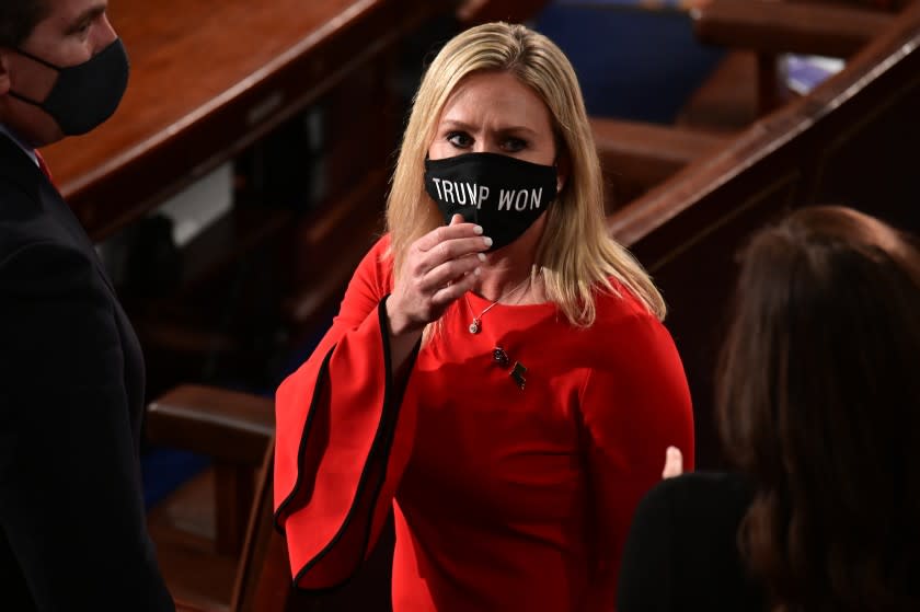 FILE - In this Sunday, Jan. 3, 2021, file photo, Rep. Marjorie Taylor Greene, R-Ga., wears a "Trump Won" face mask as she arrives on the floor of the House to take her oath of office on opening day of the 117th Congress at the U.S. Capitol in Washington. President Joe Biden's inauguration has sown a mixture of anger, confusion and disappointment among believers in the baseless QAnon conspiracy theory. Greene, who has expressed support for the conspiracy theories, called for Biden's impeachment across her Twitter, Facebook and Telegram accounts as the new president was sworn in, Wednesday, Jan. 20. (Erin Scott/Pool Photo via AP, File)