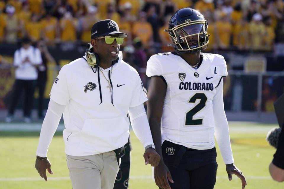 Colorado coach Deion Sanders, left, talks with his son and starting quarterback Shedeur Sanders.