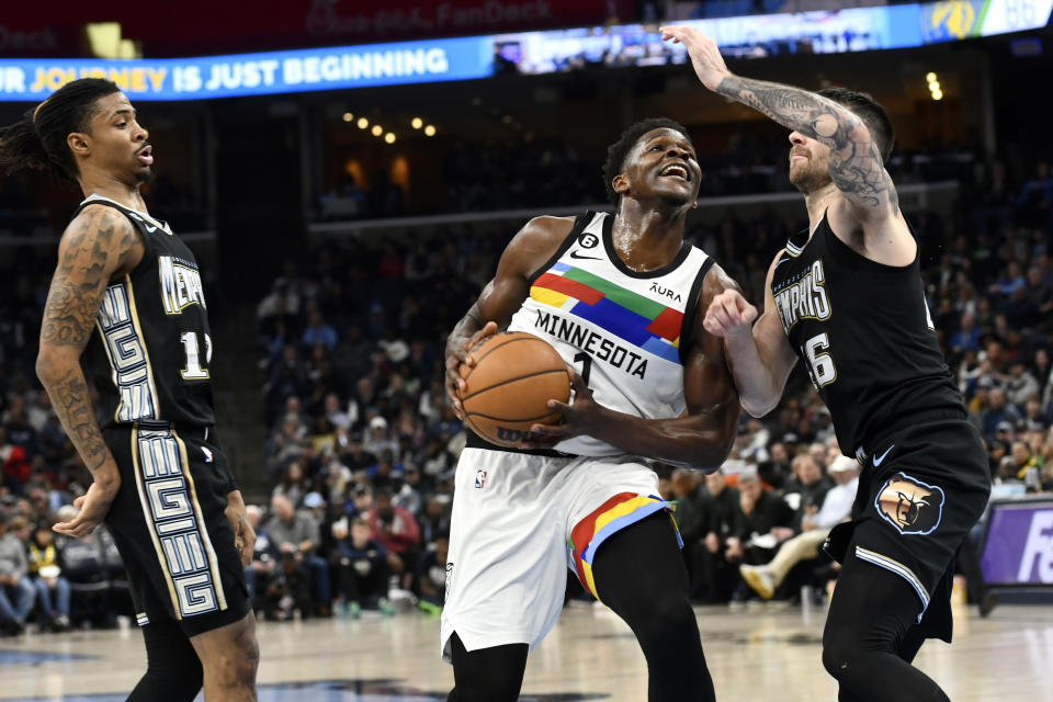 Minnesota Timberwolves guard Anthony Edwards (1) handles the ball against Memphis Grizzlies guard John Konchar, right, while guard Ja Morant, left, moves for position in the second half of an NBA basketball game Friday, Feb. 10, 2023, in Memphis, Tenn. (AP Photo/Brandon Dill)