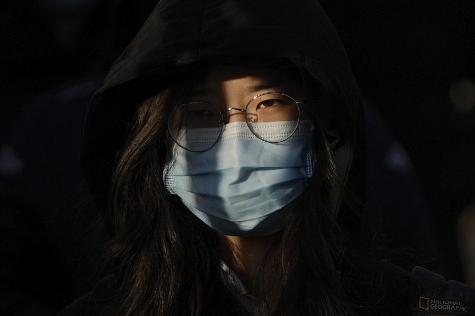 A woman wearing a face mask to protect from the coronavirus heads to work during the morning rush hour in Beijing, Monday, Jan. 10, 2022. Tianjin, a major Chinese city near Beijing has placed its 14 million residents on partial lockdown after a number of children and adults tested positive for COVID-19, including at least two with the omicron variant. (AP Photo/Andy Wong)