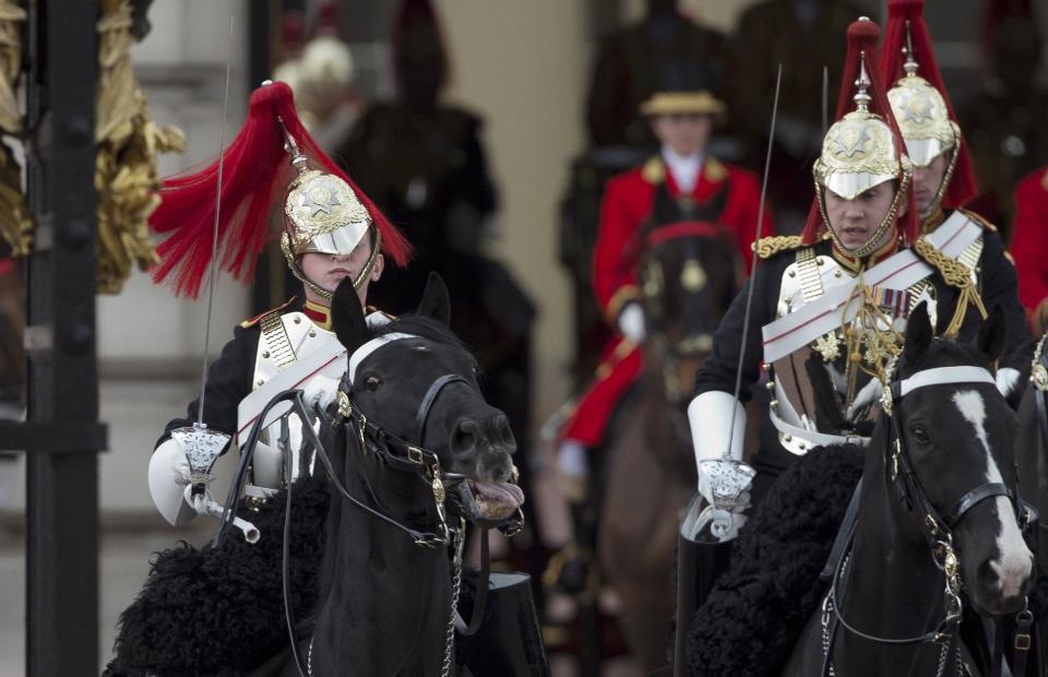 The helmet of a member of the Household Cavalry regiment, left, obscures his face as he struggles to keep control of his horse before Britain's Queen Elizabeth II left Buckingham Palace in her Irish State Coach, to deliver her speech at the State Opening of Parliament in London, Wednesday, May 8, 2013. The British government says it will announce legislation to tighten immigration rules, reform pensions and reduce red tape for business when it lays out its legislative plans for the next year. The measures will be announced by Queen Elizabeth II during the pageant of power, pomp and politics known as the State Opening of Parliament. (AP Photo/Matt Dunham)