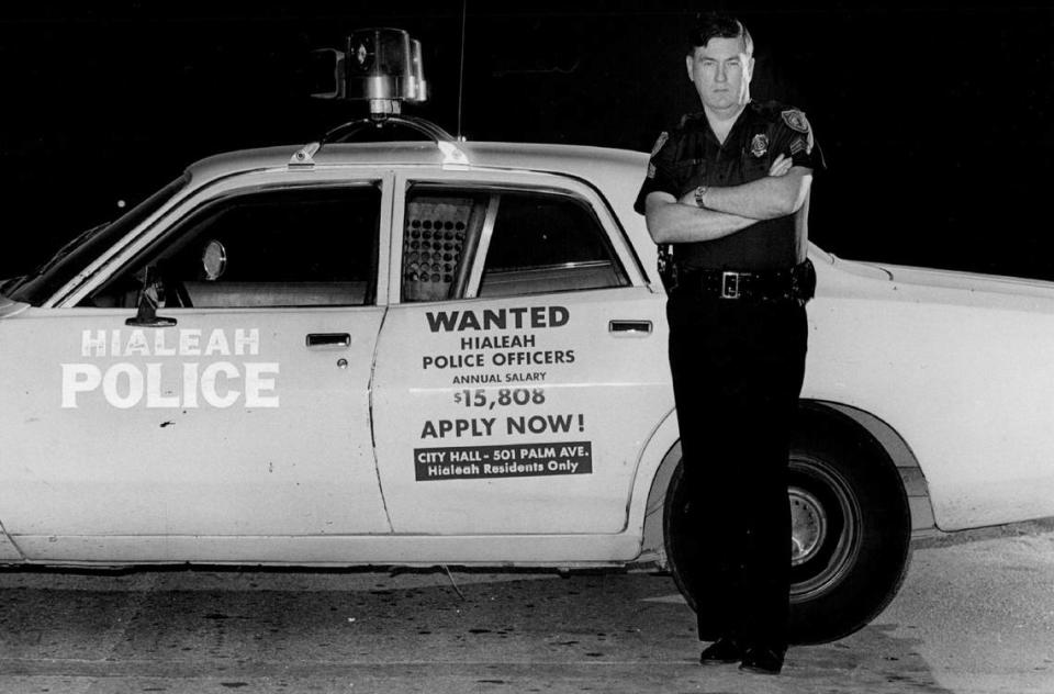 In 1980, a Hialeah police officer shows a city squad car with a sign for jobs available in English on one side and Spanish on the other.