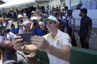 Australia's cricket captain Pat Cummins take selfie photos with fans after defeating Sri Lanka by ten wickets win in day three of the first test cricket match between Australia and Sri Lanka in Galle, Sri Lanka, Friday, July 1, 2022. (AP Photo/Eranga Jayawardena)