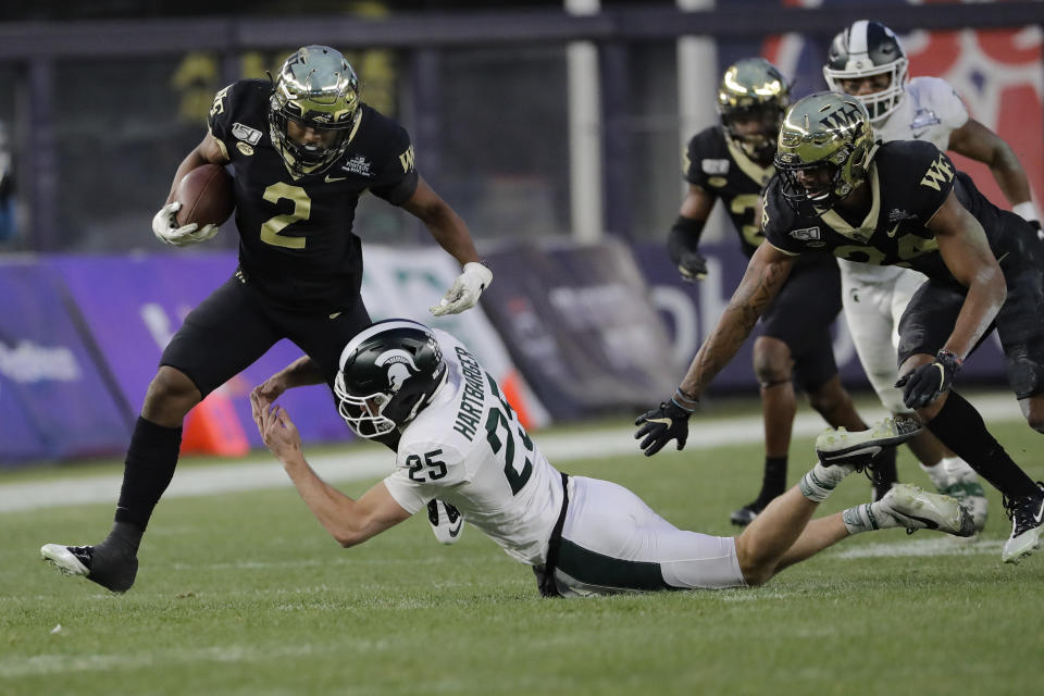 Wake Forest's Kendall Hinton (2) breaks a tackle by Michigan State's Darrell Stewart Jr. (25) during the first half of the Pinstripe Bowl NCAA college football game Friday, Dec. 27, 2019, in New York. (AP Photo/Frank Franklin II)