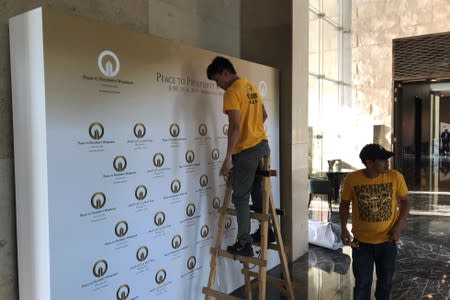 A worker places a banner at the pavilion where the U.S. hosted event "Peace to Prosperity" takes place outside Four Seasons Hotel in Manama