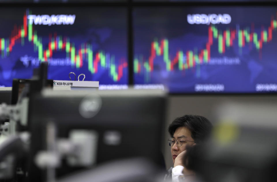 A currency trader watches computer monitors near the screens showing the foreign exchange rates at the foreign exchange dealing room in Seoul, South Korea, Tuesday, June 4, 2019. Shares are mixed in Asia after a tumultuous session for tech shares on Wall Street. (AP Photo/Lee Jin-man)