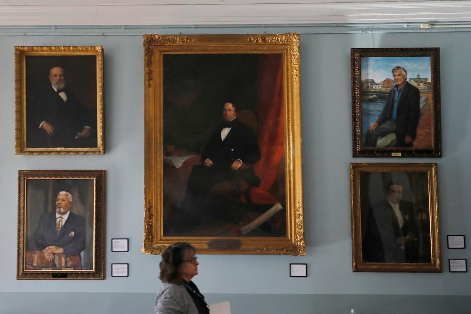 Olivia Melo, director of the New Bedford Free Public Library, walks past a painting of Abraham Howland, New Bedford's first mayor, which will be restored thanks to a donation by the Masonic Lodge of New Bedford. Sections of the painting are now obscured by years of buildup, including the city's seal which can barely be made out in the top left-hand corner.