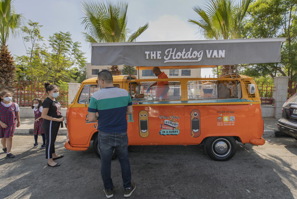 Emad Abdeljawwad sells grilled hot dogs and beverages out of a converted van in the West Bank city of Ramallah, Wednesday, Sept. 23, 2020. With dine-in restaurants mostly closed due to health restrictions, food trucks have allowed entrepreneurial palestinian businessmen to find a way to keep working. (AP Photo/Nasser Nasser)