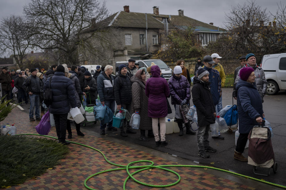 Residents queue to fill containers with drinking water in Kherson, southern Ukraine, Sunday, Nov. 20, 2022. Russian forces fired tank shells, rockets and other artillery on the city of Kherson, which was recently liberated from Ukrainian forces. (AP Photo/Bernat Armangue)