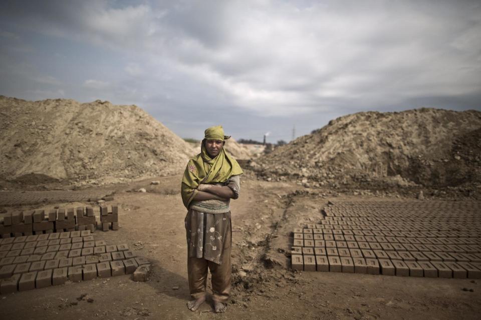 In this Wednesday, March 5, 2014, photo, Naila Liyaqat, 16, a Pakistani brick factory worker, poses for a picture at the site of her work in Mandra, near Rawalpindi, Pakistan. Naila's father is in debt to his employer the amount of 300,000 rupees (approximately $3000). (AP Photo/Muhammed Muheisen)