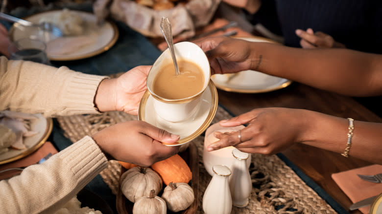 hands passing gravy boat