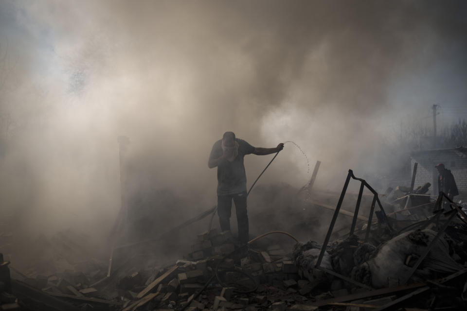 Neighbours try to extinguish the fire of a house, destroyed after a Russian attack in Kharkiv, Ukraine, Thursday, March 24, 2022. (AP Photo/Felipe Dana)