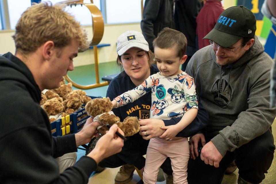 Michigan quarterback Davis Warren signs a teddy bear for Carmen Palma, 3, at C.S. Mott Children's Hospital in Ann Arbor on Friday, Jan. 12, 2024.
