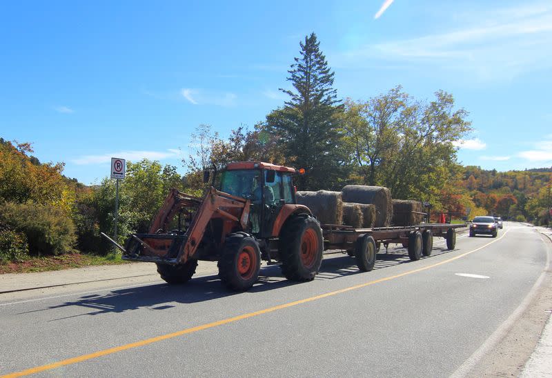 A tractor transporting hay bales travels through Wakefield village