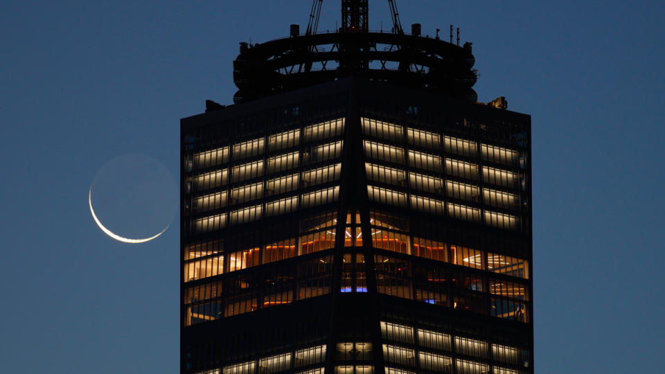 A 4 percent waning crescent moon rises behind the skyline of lower Manhattan and One World Trade Center as the sun rises in New York City on November 11, 2023, as seen from Jersey City, New Jersey.