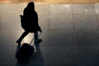 A woman pulls a suitcase at Lisbon's international airport, Tuesday, Nov. 30, 2021. Portugal is bringing back some tight pandemic restrictions, less than two months after scrapping most of them when the goal of vaccinating 86% of the population against COVID-19 was reached. (AP Photo/Armando Franca)