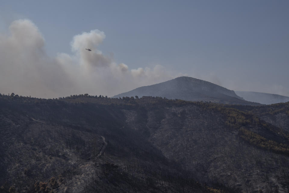 A helicopter operates near the Fyli suburb, northwest Athens, Greece, Friday, Aug. 25, 2023. Authorities battling a major wildfire in northeastern Greece that has been described as the European Union's largest single fire recorded have recovered another body, the fire department says, bringing the total death toll of wildfires in Greece this week to 21. (AP Photo/Michael Varaklas)