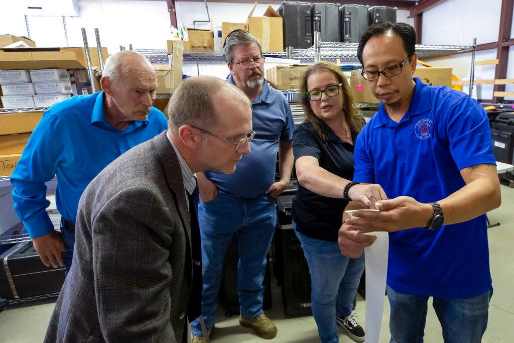 Torrance County deputy clerk Silvia Chavez, second from right, and administrative assistant clerk Kevin Pham, right, explain the tabulation receipt to local candidates and partisan officers during a ballot-counting machines testing in Estancia, N.M., Sept. 29, 2022.