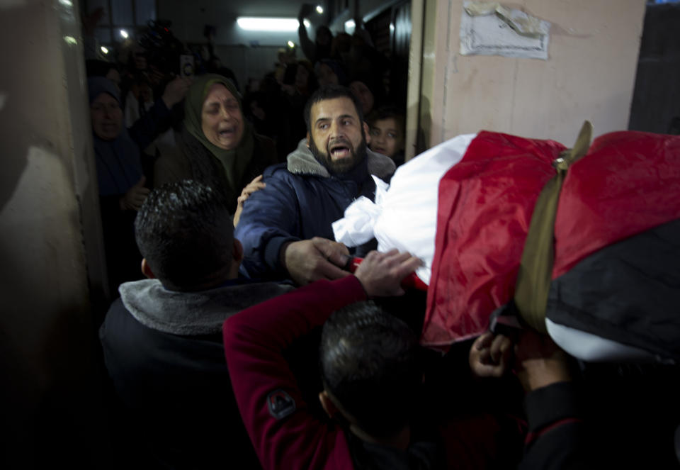 Mourners carry the body of Palestinian woman, Amal al-Taramsi, 43, who was killed by Israeli troops during Friday's protest at the Gaza Strip's border with Israel, into the family home during her funeral in Gaza City, Saturday, Jan. 12, 2019. (AP Photo/ Khalil Hamra)