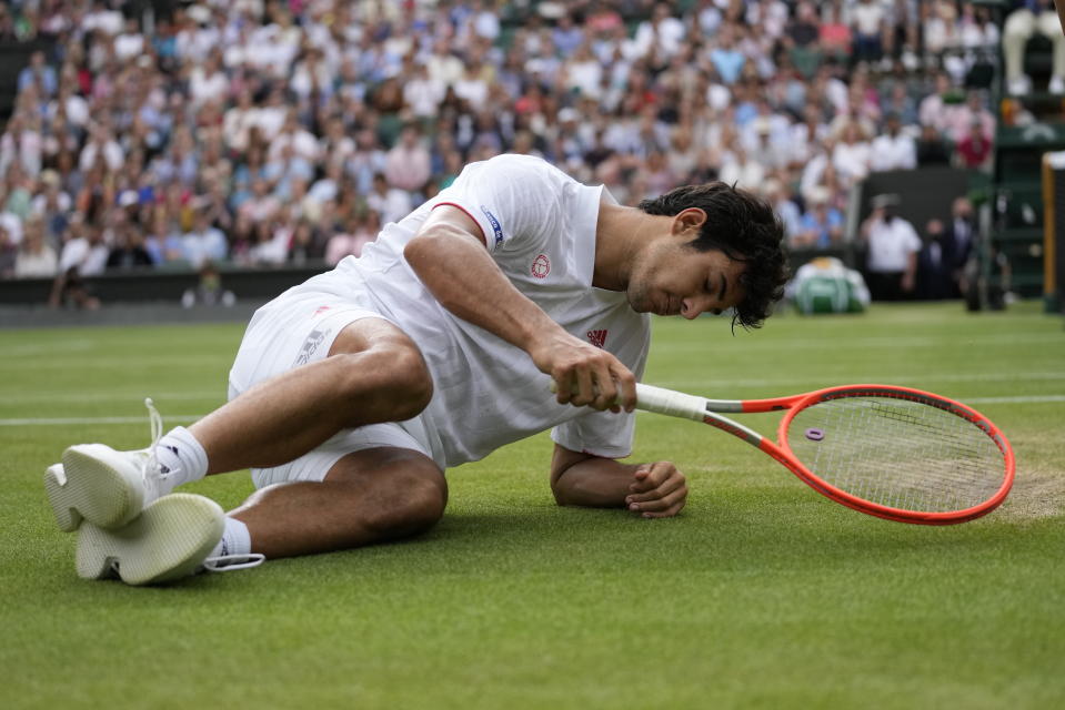 Cristian Garín sufre una caída durante el duelo contra Novak Djokovic por la cuarta ronda del torneo de Wimbledon, el lunes 5 de julio de 2021, en Londres. (AP Foto/Kirsty Wigglesworth)