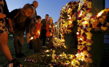 A woman places an electronic candle among flowers at the site where the words "Keep Hope Alive" were spelt in a floral tribute, calling on Indonesia to halt the planned execution of two convicted Australian drug traffickers on death row, during a candlelight vigil held by Amnesty International in Sydney, Australia, April 27, 2015. REUTERS/Jason Reed