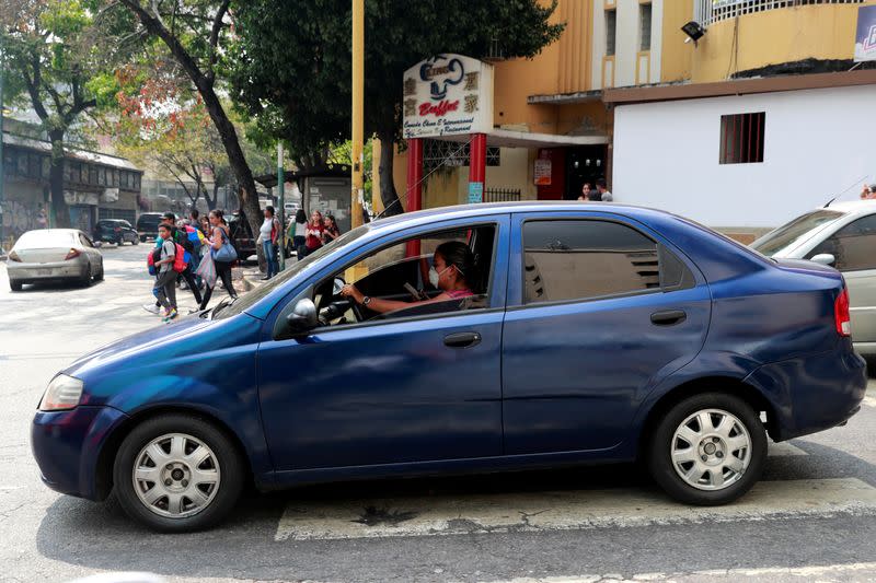 A woman wears a protective while driving a car in response to coronavirus (COVID-19) spread, in Caracas