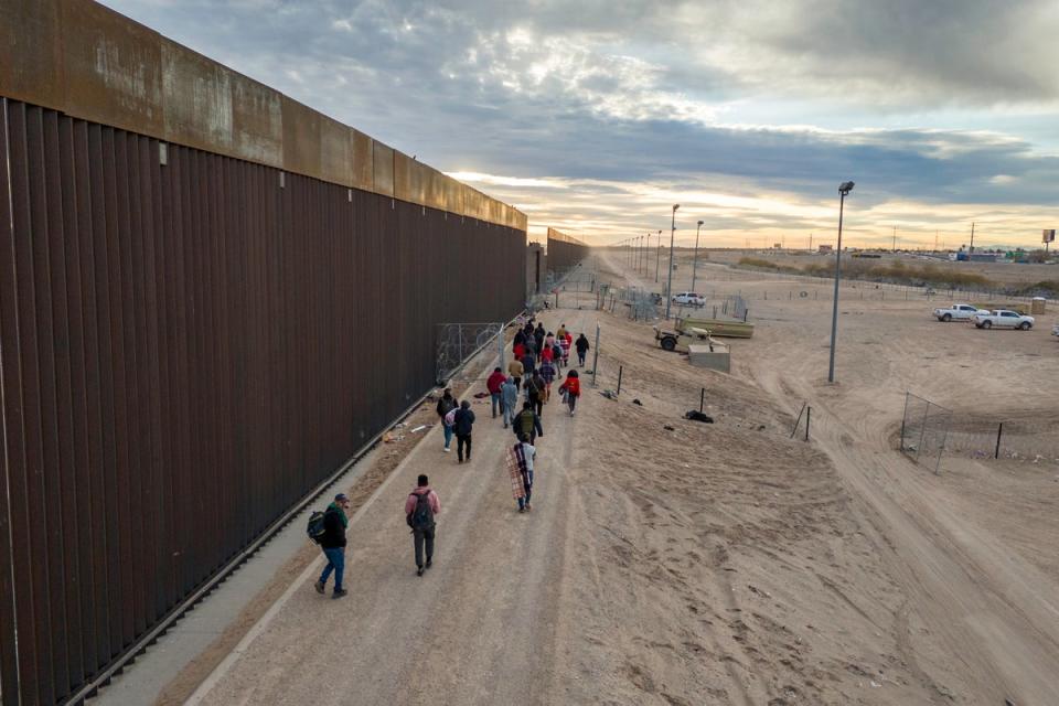 Seen from an aerial view, immigrants walk along the U.S.-Mexico border wall after crossing the Rio Grande into El Paso, Texas on 1 February 2024 from Ciudad Juarez, Mexico (Getty Images)