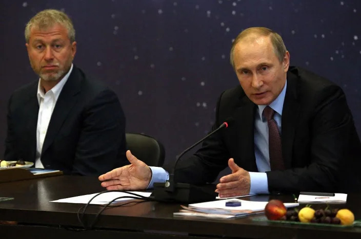 Russian President Vladimir Putin (R) speaks as billionaire and businessman Roman Abramovich (L) looks on during a meeting with top businessmen