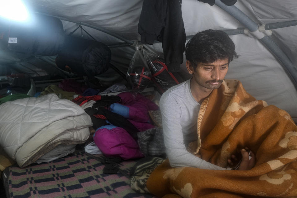 A migrant sits in a tent at the Lipa camp, outside Bihac, Bosnia, Monday, Jan. 11, 2021. Aid workers say migrants staying at a camp in northwestern Bosnia have complained or respiratory and skin diseases after spending days in make-shift tents and containers amid freezing weather and snow blizzards. Most of the hundreds of migrants at the Lipa facility near Bosnia's border with Croatia on Monday have been accommodated in heated military tents following days of uncertainty after a fire gutted most of the camp on Dec. 23.(AP Photo/Kemal Softic)