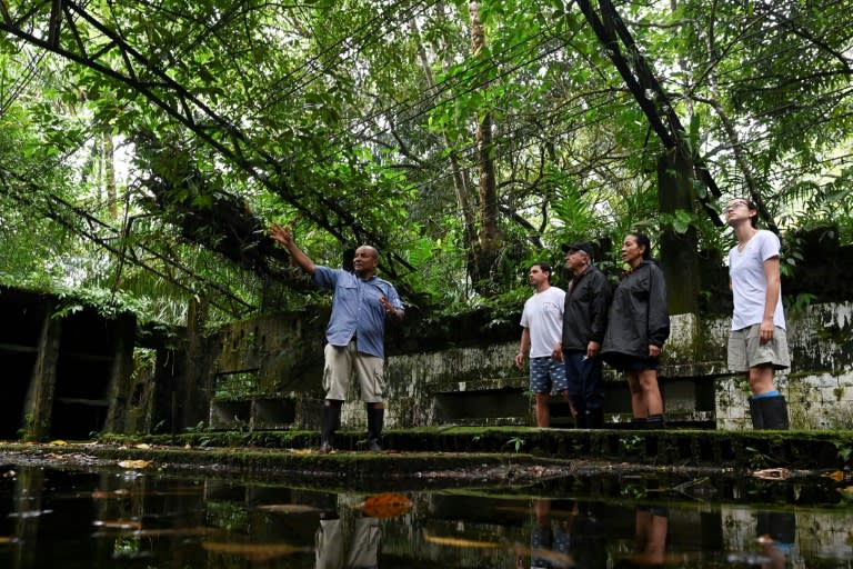 Corazon de Jesus Aguino (à gauche), technicien du parc, fait visiter l'ancien bagne colombien de La Gorgone à des touristes, le 2 décembre 2021 (AFP/Luis ROBAYO)