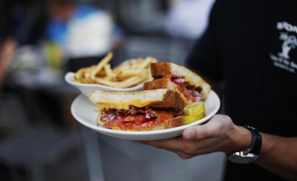 In this July 30, 2013 photo, Justin Glass holds a grilled cheese sandwich platter at Stoney's Lounge in Washington. Stoney's is located in the Logan Circle neighborhood of Washington. (AP Photo/Pablo Martinez Monsivais)