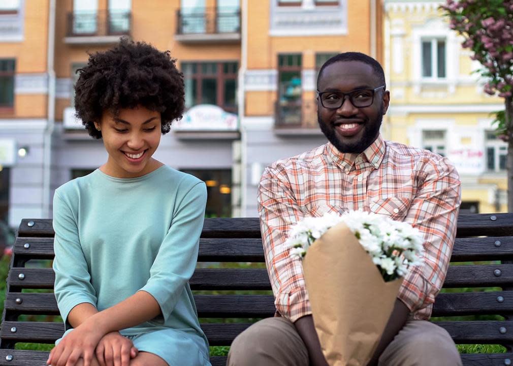 woman and man sit awkwardly on a bench on a date