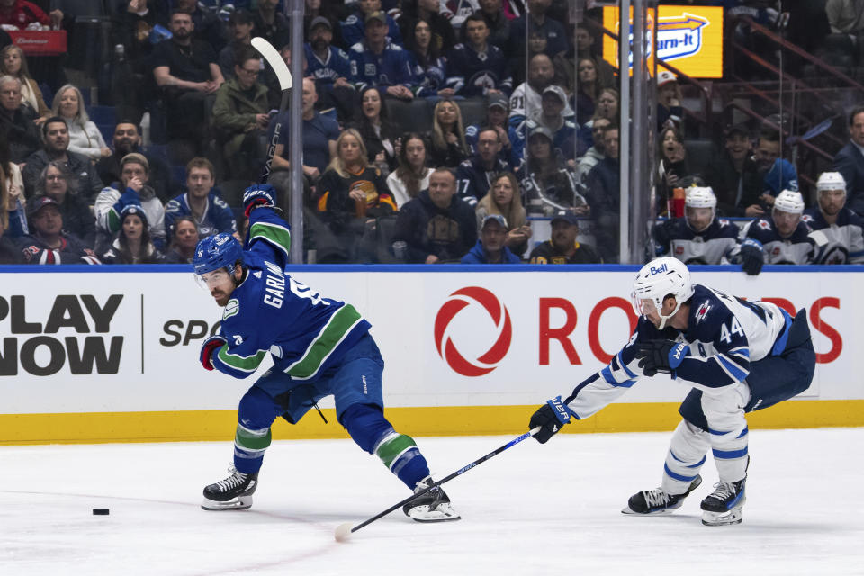 Vancouver Canucks' Conor Garland (8) winds up for a shot as Winnipeg Jets' Josh Morrissey (44) reaches for the puck during the first period of an NHL hockey game Saturday, March 9, 2024, in Vancouver, British Columbia. (Ethan Cairns/The Canadian Press via AP)