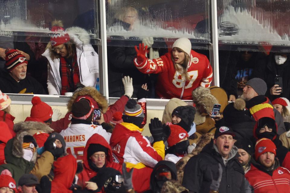 Taylor Swift gives fans a high-five during the NFL playoff matchup between the Chiefs and Dolphins.