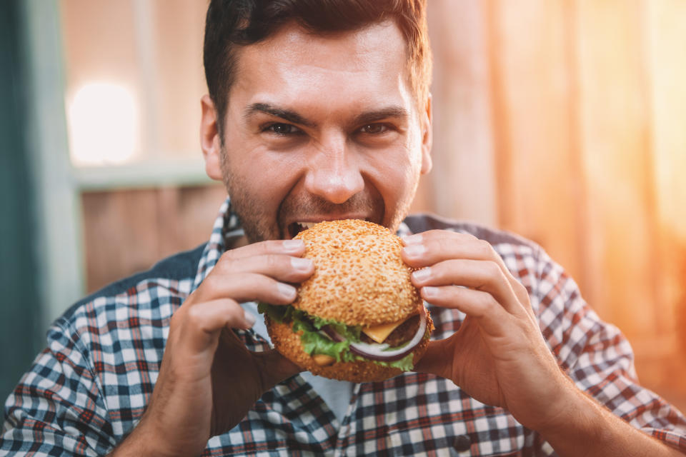 A man bites into a burger.