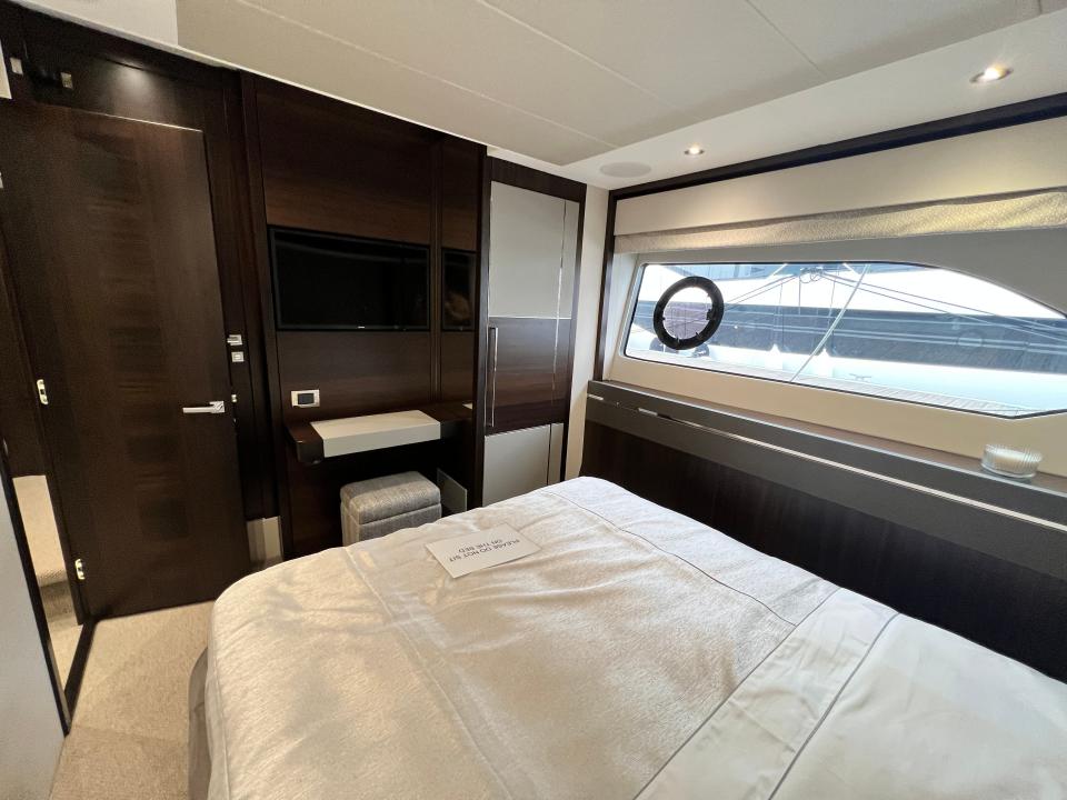 A television, dressing table and narrow wardrobe viewed from the end of a guest cabin onboard Sunseeker 76