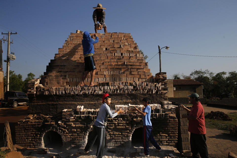 Children work with their relatives to load a kiln with clay bricks in Tobati, Paraguay, Friday, Sept. 4, 2020. In many of the small Tobati brick factories, locals begin to work at an early age to complement their family's income. (AP Photo/Jorge Saenz)