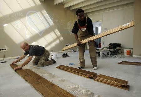 Tesfagebriel Abraha of Eritrea (R), 31, carries planks while working as an apprentice for a parquet recliner in Dortmund, Germany, August 31, 2015. REUTERS/Ina Fassbender/Files