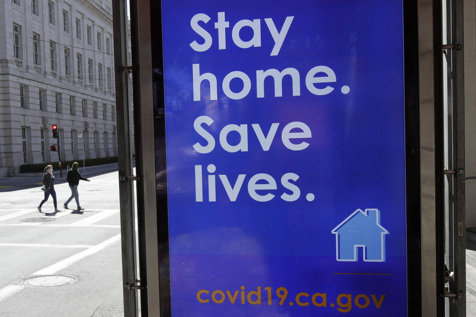 FILE - In this April 2, 2020, file photo, a sign advising people to stay home due to COVID-19 concerns is displayed at a MUNI bus stop in San Francisco. The city has suffered a large exodus, both in housing and people working in offices. When the lockdown order came in March 2020, an estimated 137,500 workers for companies that include Google, Facebook and Uber, seemingly vanished overnight. Moving vans carted off entire households for roomier suburban homes and younger people simply packed up their cars and left since they could work from anywhere. Residential rents plummeted, but are now climbing back up. Rent prices have gone down 10% in San Francisco but remained stable in Los Angeles. (AP Photo/Jeff Chiu, File)