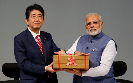 Japanese Prime Minister Shinzo Abe (L) and his Indian counterpart Narendra Modi hold a replica of a brick during the India-Japan Annual Summit, in Gandhinagar, India, September 14, 2017. REUTERS/Amit Dave