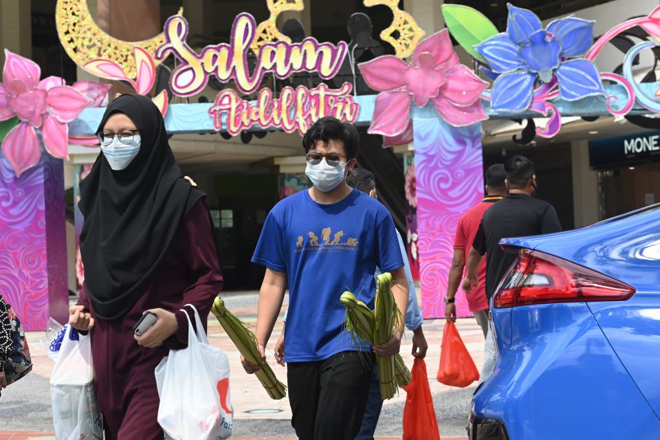 People wearing face masks amid concern over the spread of the COVID-19 coronavirus crosses a road with building displays of festive decorations ahead of Eid al-Fitr which marks the end of the Muslim holy month of Ramadan, at the Geylang Serai market in Singapore on May 21, 2020. (Photo by Roslan RAHMAN / AFP) (Photo by ROSLAN RAHMAN/AFP via Getty Images)