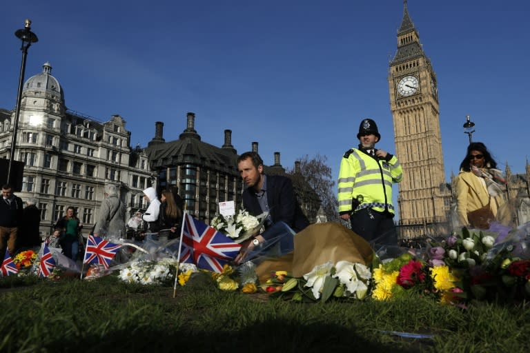 People lay floral tributes to the victims of the March 22 terror attack in Parliament Square outside the Houses of Parliament in central London