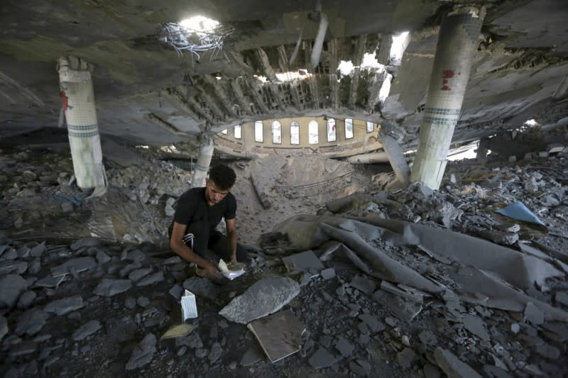 <cite>2023年10月8日，一名男子在加薩走廊一座清真寺內查看在以色列空襲中被毀壞的書籍。（美聯社）</cite>