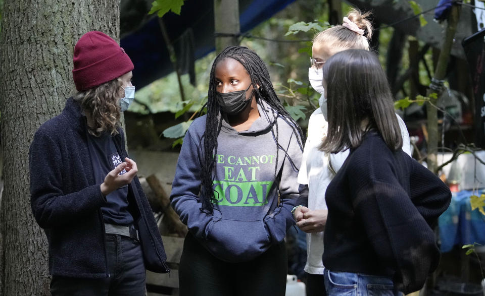 Climate activist Vanessa Nakate from Uganda, 2nd left, visits an activist camp in a forest near the Garzweiler open-cast coal mine in Keyenberg, western Germany, Saturday, Oct. 9, 2021. Garzweiler, operated by utility giant RWE, has become a focus of protests by people who want Germany to stop extracting and burning coal as soon as possible. (AP Photo/Martin Meissner)