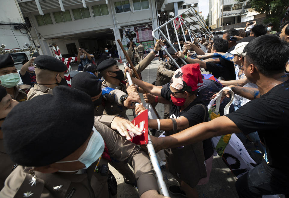 Anti-government protesters push a metal barrier into inside of the Samranrat police station in Bangkok, Thailand, Friday, Aug, 28, 2020. The protesters tussled with police in the Thai capital on Friday as 15 of their movement leaders turned up at a police station to answer a summons linked to demonstrations denouncing the arrests. (AP Photo/Sakchai Lalit)