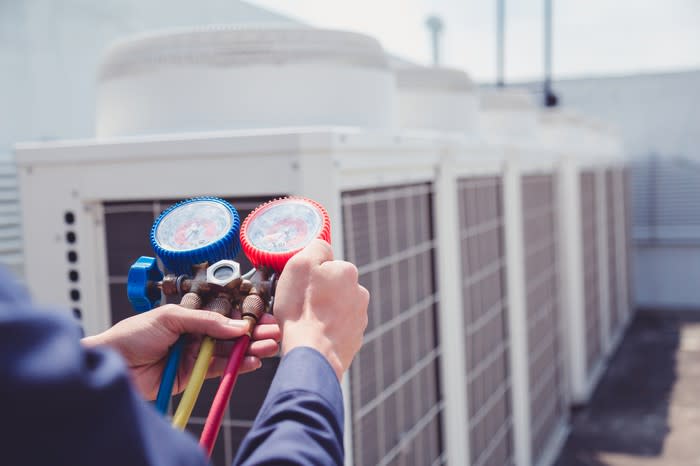 An HVAC technician checking readings on a commercial air conditioning system.