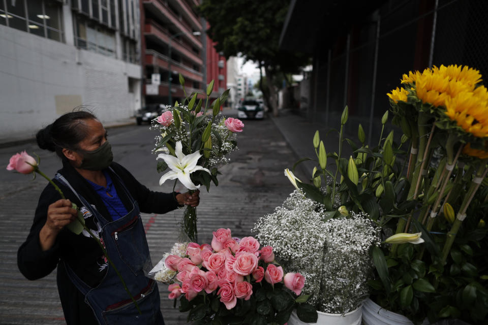 Lucia Nieto assembles an arrangement of flowers for a customer, as she, her husband, and daughter sell fresh flowers from their family cart, in central Mexico City, Sunday, May 31, 2020. Mexico's capital plans to reopen certain sectors of the economy and public life beginning Monday, despite the city still being in the most serious "red light" phase of the coronavirus pandemic. (AP Photo/Rebecca Blackwell)