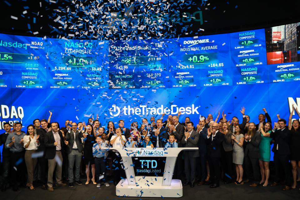 A group of people at the NASDAQ with confetti falling and The Trade Desk logo on the wall behind them.