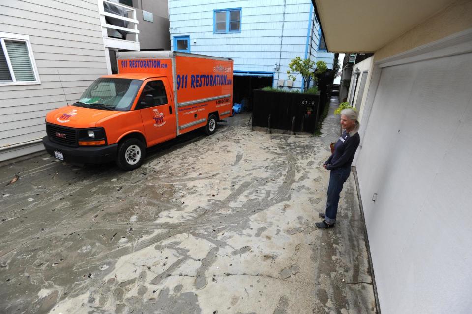 Sandy Wilson checks out the damage to her neighbor's home where sand and silt flooded the home and garage near Ocean Boulevard between 66th and 72nd Place, along the Peninsula in Long Beach, Calif., Sunday, March 2, 2014. Flooding occurred when heavy surf eroded the protective sand berm Saturday night, resulting in 20 homes on Ocean Blvd between 66th and 72nd Place, sustaining damage to either living levels or parking areas. No residents were reported to be displaced, said Long Beach Fire Department Public information Officer Will Nash. (AP Photo/Daily Breeze, Stephen Carr)