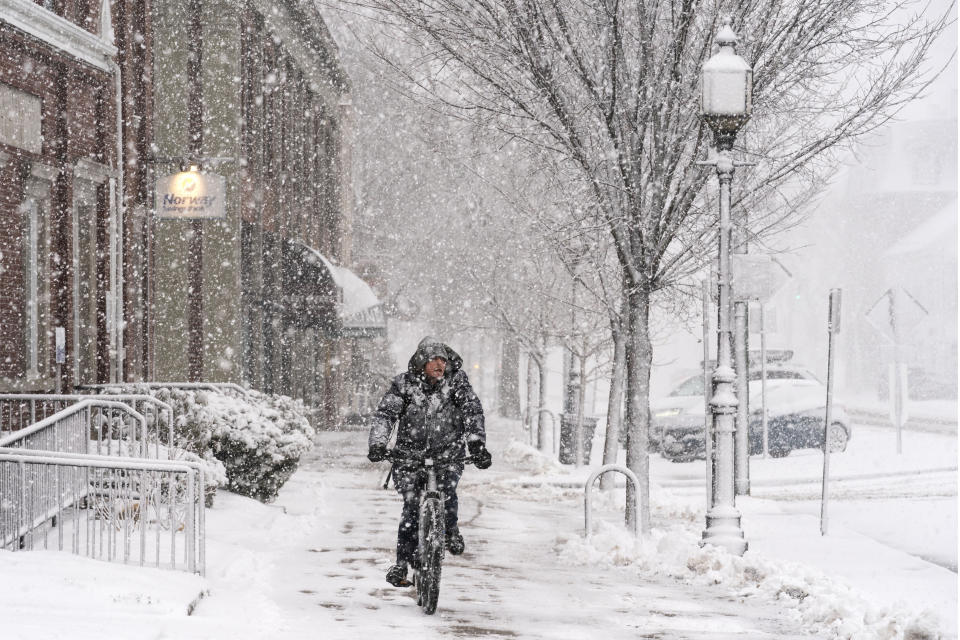 Corey Baird rides his knobby-tired mountain bike on a slippery sidewalk while peddling to a grocery store during a heavy snowfall, Tuesday, March 14, 2023, in Brunswick, Maine. (AP Photo/Robert F. Bukaty)